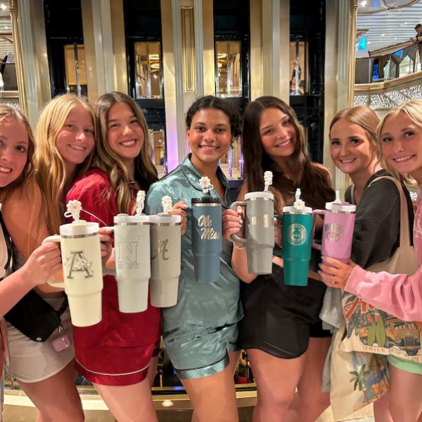 Group of six women holding personalized tumblers in a store setting